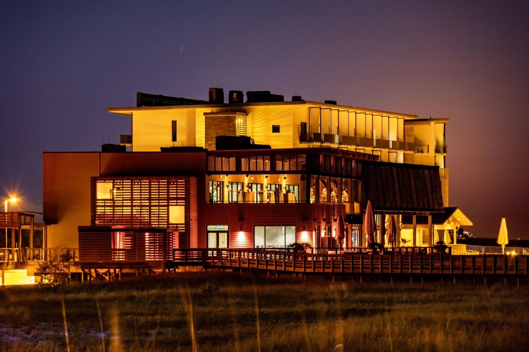 Modern building lit up at night, reflected in waterfront