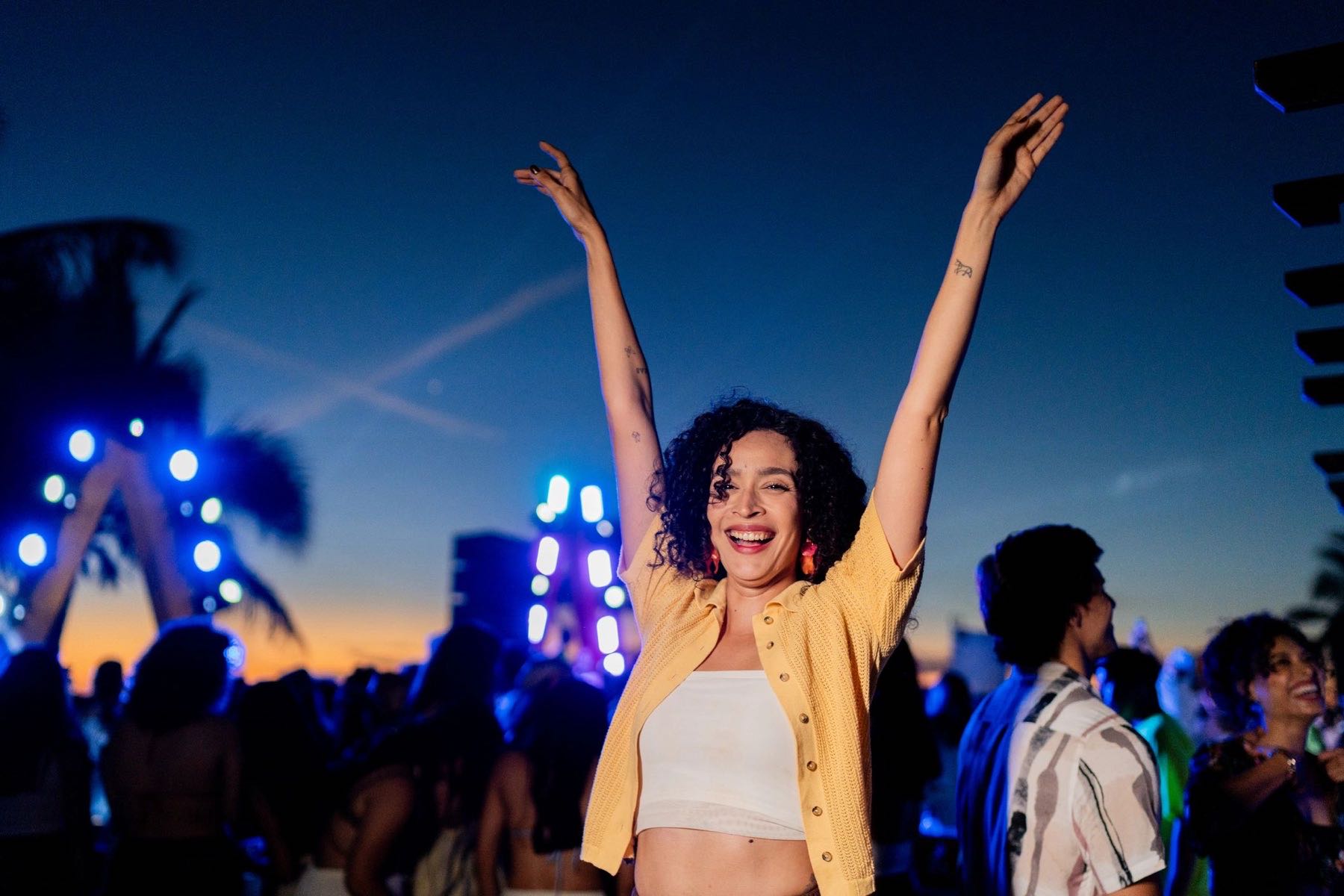 Woman with arms raised at a sunset festival event