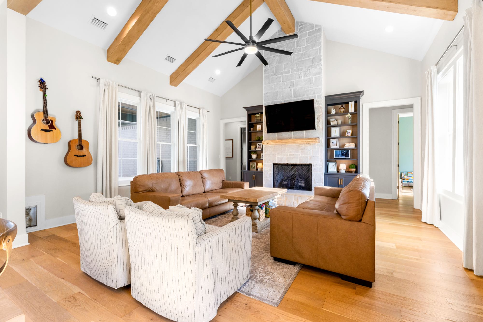 Open great room with wood beam ceiling and leather sofas