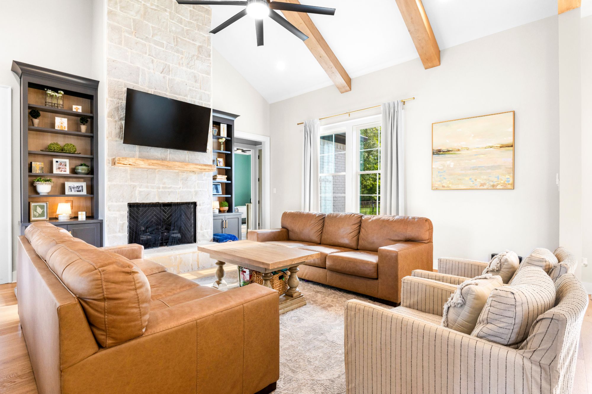 Vaulted living room with a stone fireplace and leather seating