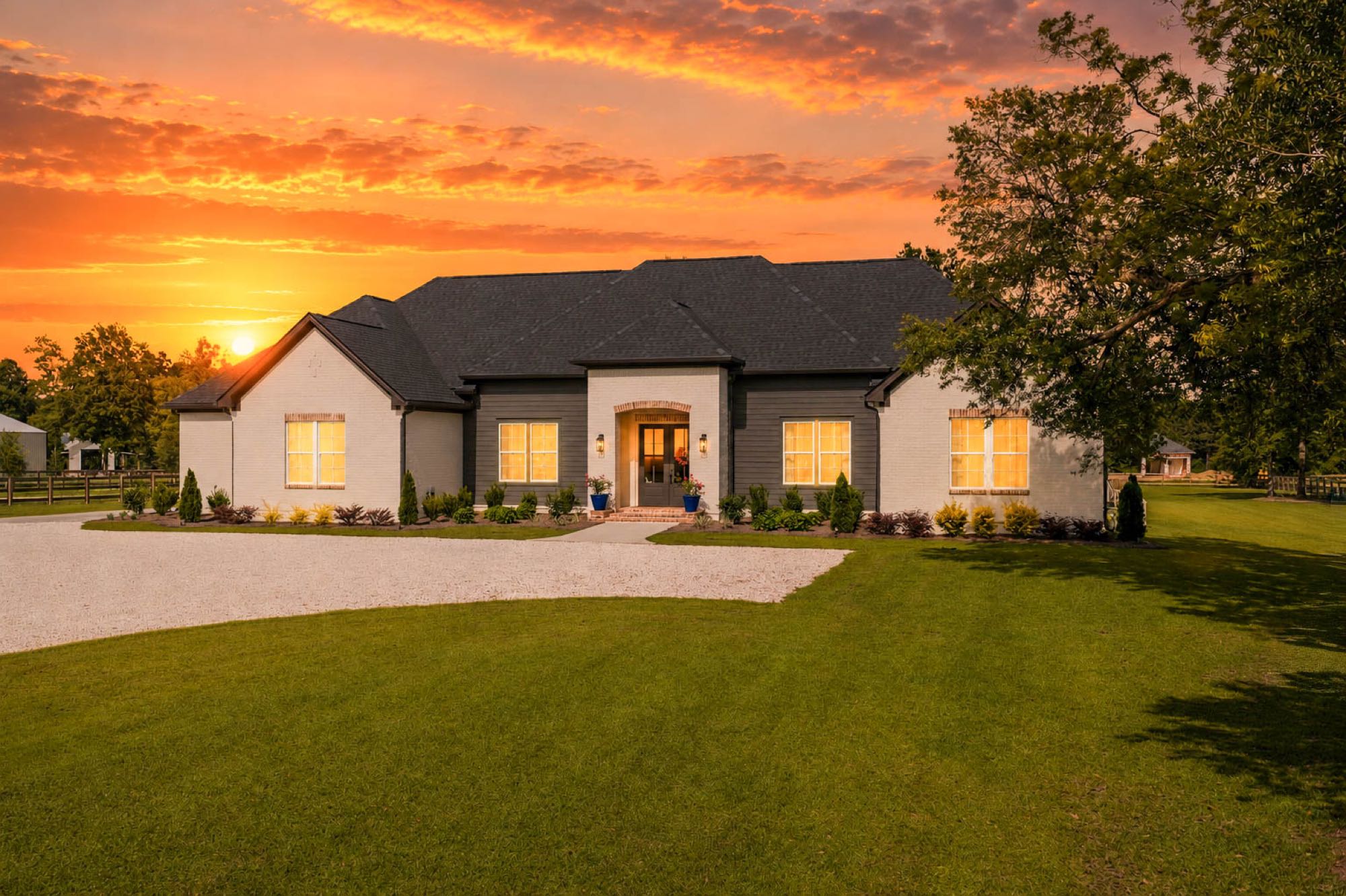Modern farmhouse at twilight with a dramatic orange sunset sky
