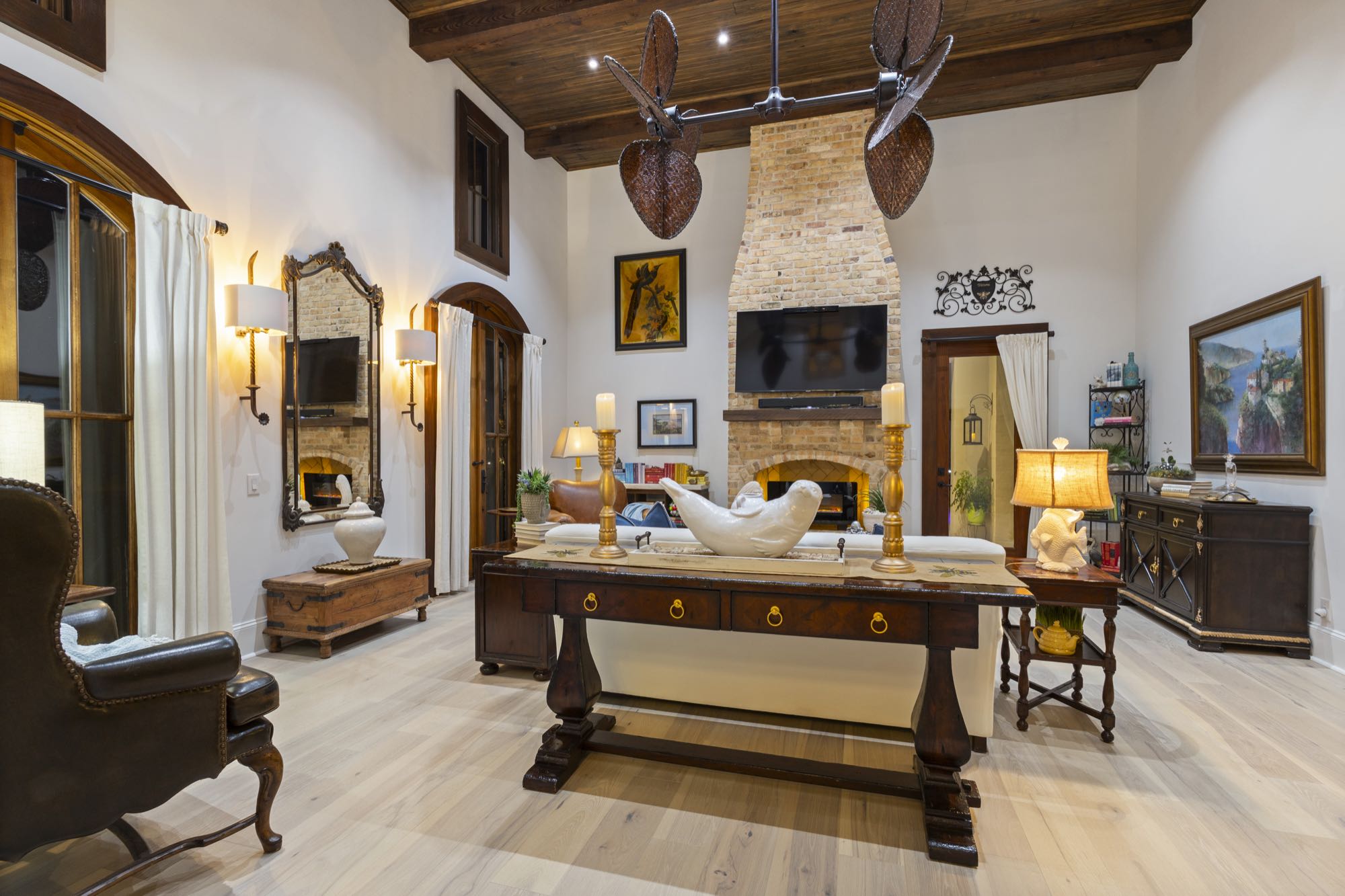 Cozy den with stone fireplace, wood beams, and leather seating