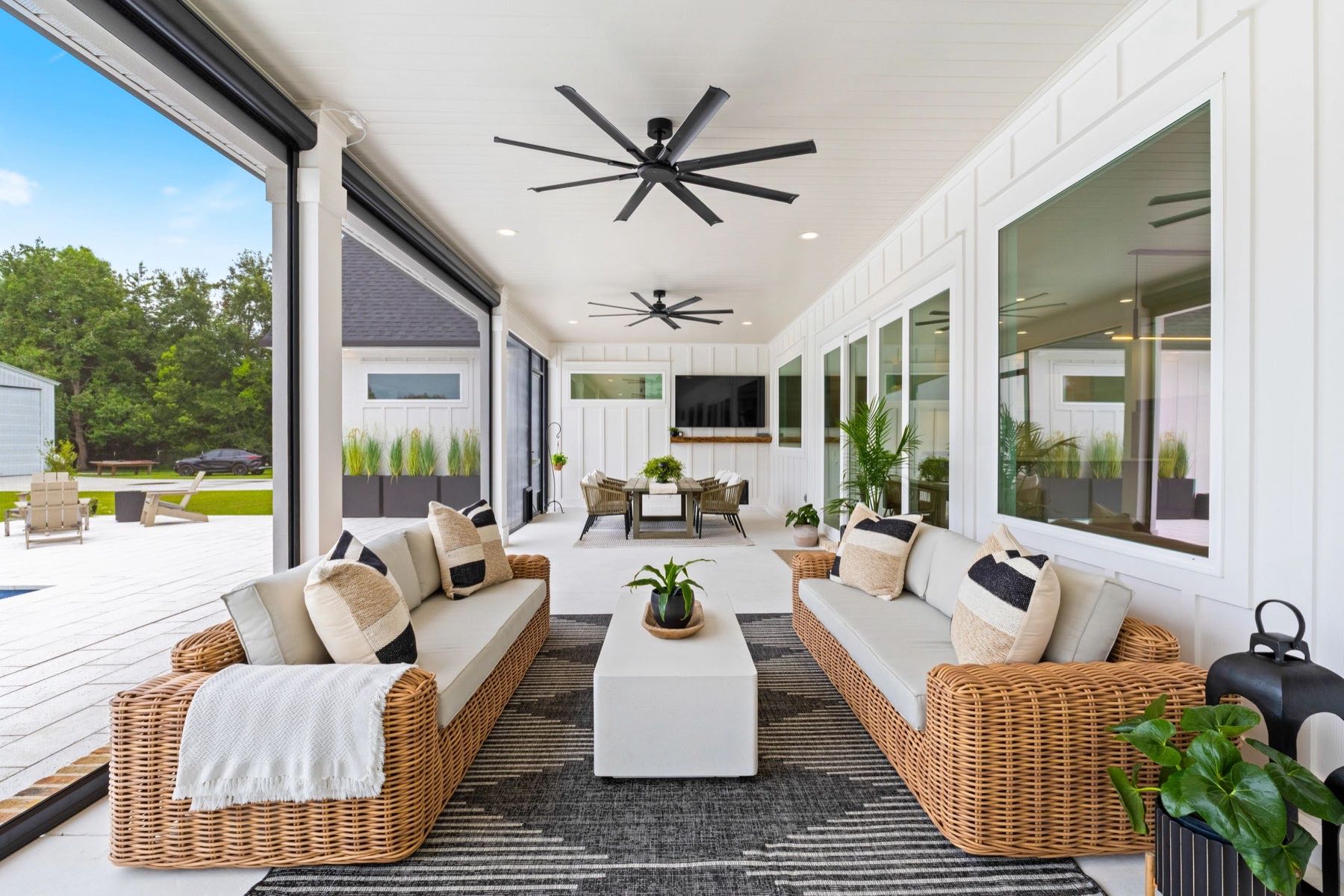 Covered outdoor patio with wicker furniture and ceiling fans