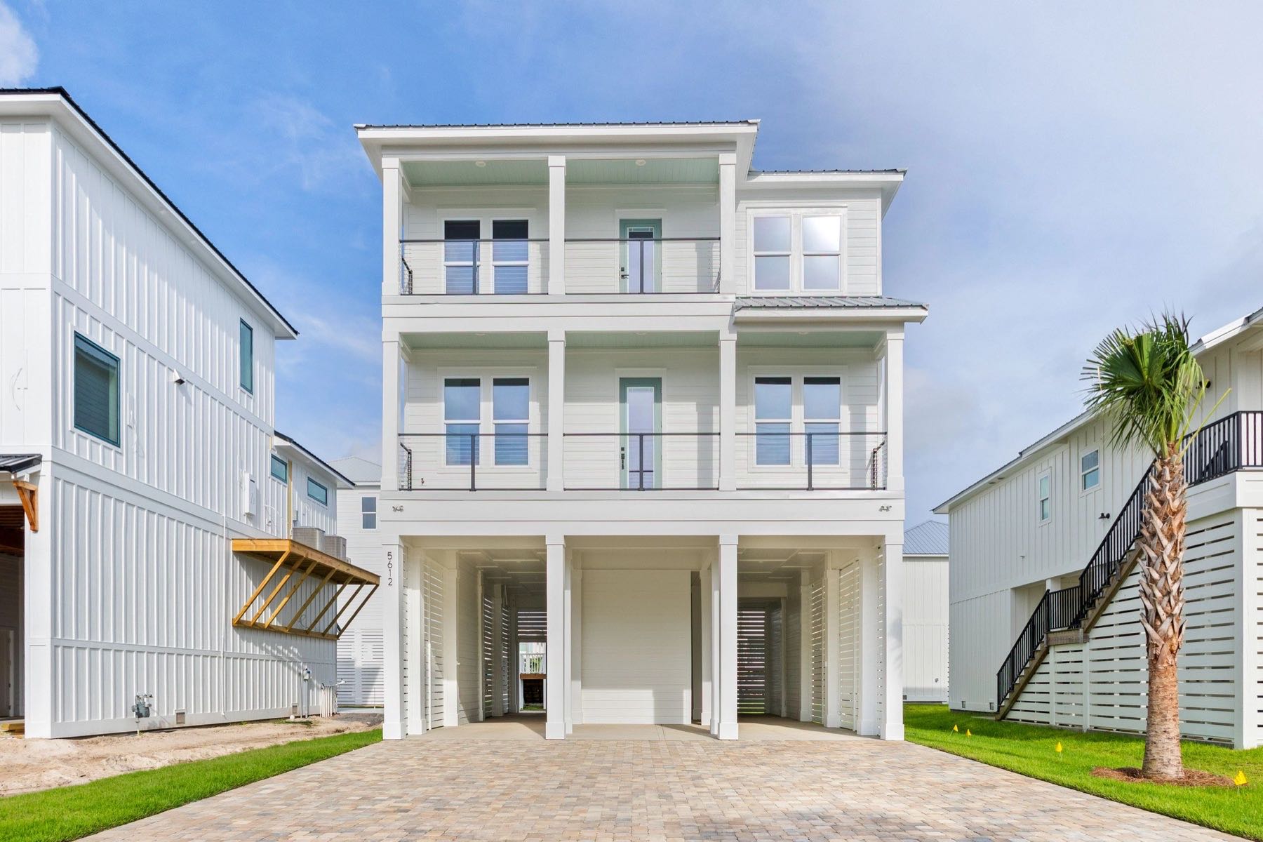 Three-story coastal home with balconies and palm trees